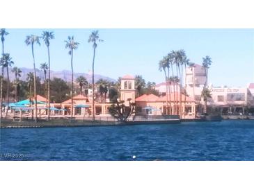 Stunning lakefront view with palm trees, beach access, and building with tower under clear sky at 3151 Soaring Gulls Dr # 2035, Las Vegas, NV 89128