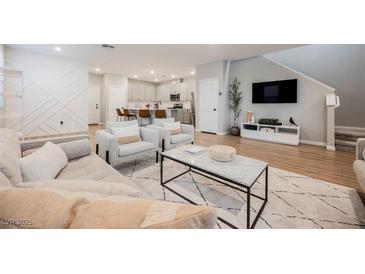 Bright and airy living room featuring a modern kitchen view, stylish decor, and hardwood floors at 3525 Serravalle Ln, Henderson, NV 89044