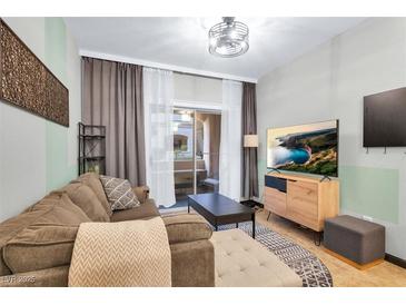 Comfortable living room with a brown sofa and sliding glass doors to a balcony area with seating at 5751 E Hacienda Ave # 119, Las Vegas, NV 89122