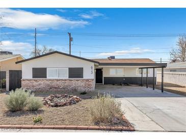 Charming single-story home with a brick facade, desert landscaping, and a covered carport on a sunny day at 613 Kings Pl, Boulder City, NV 89005