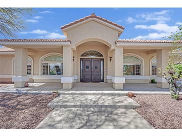 Inviting front entrance with an arched doorway and manicured landscaping at 8945 S Tenaya Way, Las Vegas, NV 89113