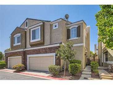 Charming townhome with a combination of stucco and brick exterior, plus a two-car garage and landscaped front yard at 939 Paisley St, Las Vegas, NV 89145