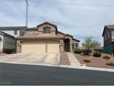 Two-story home featuring a three car garage, steps leading to the front door, and desert landscaping at 10650 Robin Hill Ave, Las Vegas, NV 89129