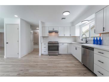 Bright white kitchen featuring stainless steel appliances, light wood floors and modern backsplash at 1808 E Saint Louis Ave, Las Vegas, NV 89104