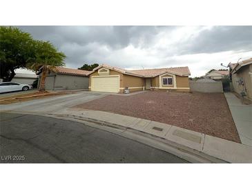 Tan single-story home featuring a two-car garage and low maintenance rock landscaping at 5135 Shimmering Peak Way, North Las Vegas, NV 89031