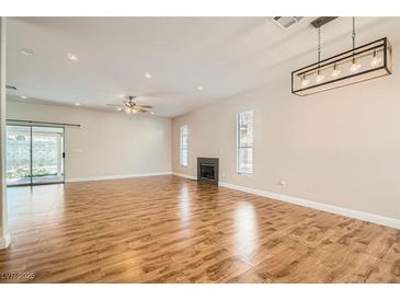Bright living room boasts wood floors, fireplace, and modern light fixture at 5921 Royal Castle Ln, Las Vegas, NV 89130