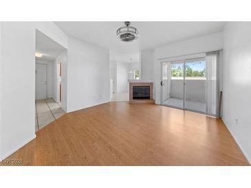 Bright living room featuring wood floors, a fireplace, and a sliding glass door to outdoor space at 10116 Jacob Pl # 104, Las Vegas, NV 89144