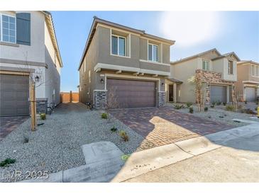 Two-story home featuring a two-car garage, brick paved driveway, and low maintenance landscaping at 10328 Apefly St, Las Vegas, NV 89141