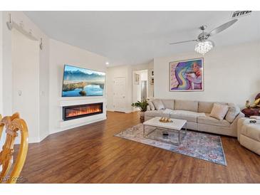 Open living room features a fireplace, flatscreen TV, elegant fan, and hardwood floors at 11013 Mission Lakes Ave, Las Vegas, NV 89134