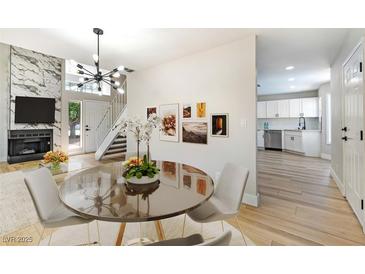 Open-concept living room features a fireplace, dining area, and pass-through to an all-white kitchen at 416 Greenbrook St, Las Vegas, NV 89110