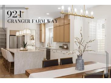 Bright kitchen with island seating, stainless appliances, and wood grain cabinets at 921 Granger Farm Way, Las Vegas, NV 89145