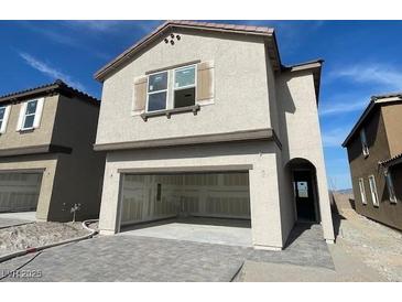 Two-story home featuring an open garage, neutral stucco, and stylish architectural details at 9556 Hinson St, Las Vegas, NV 89139