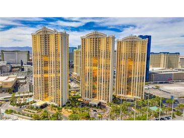 Striking high-rise condos with golden windows and manicured landscaping under a bright blue, cloud-strewn sky at 135 E Harmon Ave # 804, Las Vegas, NV 89109