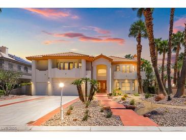 Elegant two-story home featuring a tile roof, palm trees, and an inviting walkway at 1840 Myrtle Island Dr, Las Vegas, NV 89117
