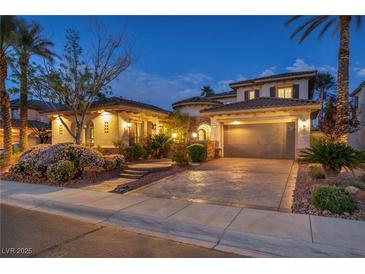Stunning two-story home featuring lush landscaping and a spacious three-car garage at twilight at 1994 Orchard Mist St, Las Vegas, NV 89135
