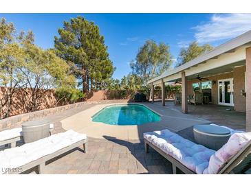 Backyard pool area showcasing a luxurious lounge area, sparkling pool water, and beautiful landscaping on a sunny day at 2246 Almart Cir, Henderson, NV 89014