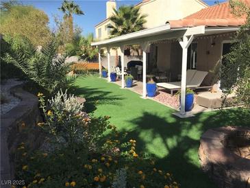 Inviting backyard with covered patio, lush landscaping, and artificial turf for easy maintenance and outdoor living at 2747 Sandalwood Ave, Henderson, NV 89074