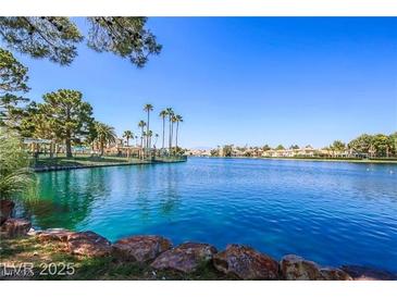 Scenic view of the community lake, with palm trees and lush landscaping under a clear blue sky at 3151 Soaring Gulls Dr # 1201, Las Vegas, NV 89128