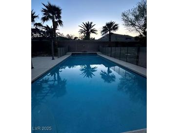 Inviting backyard pool with palm trees and a safety fence ensures relaxation and peace of mind at 7451 Mystic Stream St, Las Vegas, NV 89131