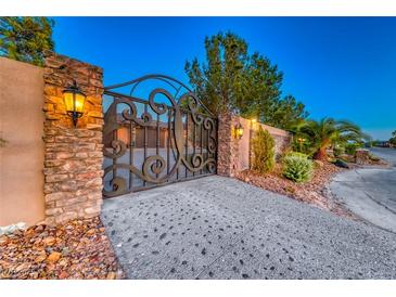 Ornate iron gate with stone pillars and landscape lighting at 9920 Rancho Destino Rd, Las Vegas, NV 89183