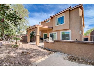 A spacious backyard with covered patio, gravel landscaping, and a view of the home's exterior at 11120 Whooping Crane Ln, Las Vegas, NV 89144