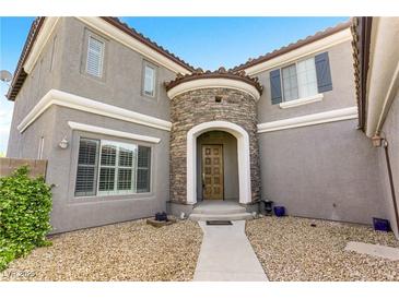 Charming two-story home showcasing a stone turret entry, a welcoming walkway, and desert landscaping at 10013 Scenic Walk Ave, Las Vegas, NV 89149