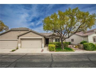 Inviting single-story home featuring a two-car garage, mature landscaping, and a well-maintained front yard at 10980 Ampus Pl, Las Vegas, NV 89141