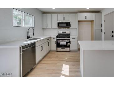 Bright kitchen features stainless steel appliances, white cabinets and quartz countertops at 1304 Virgil St, Las Vegas, NV 89110