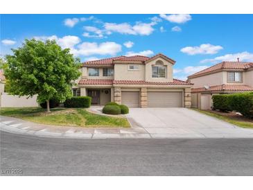 Two-story home with a red tile roof, three car garage and landscaped front yard on a sunny day at 7632 Spruce Run Ct, Las Vegas, NV 89128