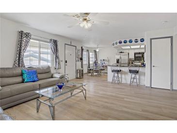 Bright living room with modern furnishings, light wood floors and a view to the open kitchen at 8410 Eldora Ave # 2082, Las Vegas, NV 89117
