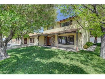 Charming two-story home with a stone facade porch, lush green lawn, and mature trees providing shade at 8970 W Lone Mountain Rd, Las Vegas, NV 89129