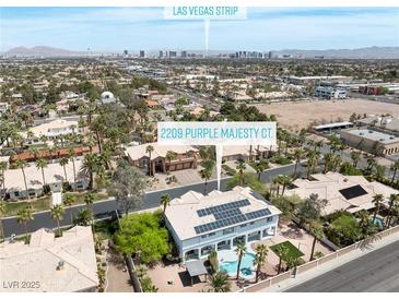Aerial view of home on Purple Majesty Ct. featuring a pool, solar panels and a view of the Las Vegas strip at 2209 Purple Majesty Ct, Las Vegas, NV 89117