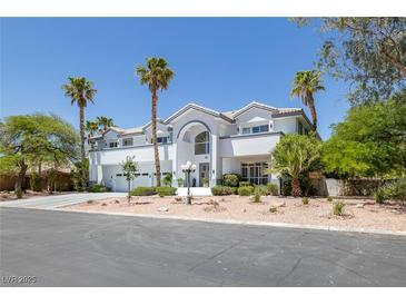 Elegant two-story home with arched entryway, lush landscaping, and multiple palm trees, offering curb appeal at 2209 Purple Majesty Ct, Las Vegas, NV 89117