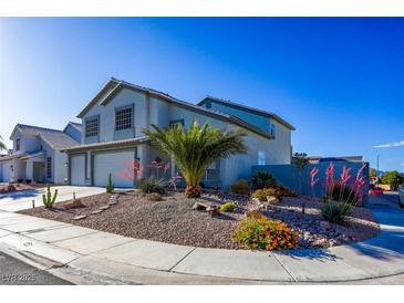 Charming two-story home with a two-car garage and desert landscaping, including a palm tree and colorful flowering shrubs at 7800 Four Seasons Dr, Las Vegas, NV 89129