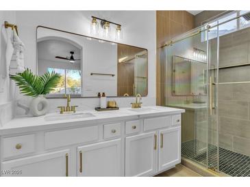 Modern bathroom featuring a double vanity with marble countertop and a sleek glass-enclosed shower at 10200 Wood Work Ln, Las Vegas, NV 89135