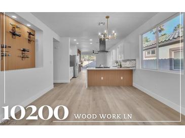Bright, open kitchen boasts white cabinets, island, and modern light fixtures at 10200 Wood Work Ln, Las Vegas, NV 89135