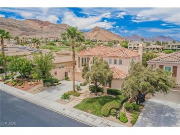 Elegant two-story house boasts lush landscaping, desert mountains, and a charming Mediterranean-style terracotta tile roof at 11534 Glowing Sunset Ln, Las Vegas, NV 89135