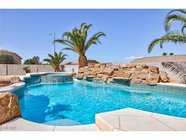 Inviting backyard pool with rock waterfall feature and lush tropical landscaping at 6638 Dazzling Heights Ln, Las Vegas, NV 89110