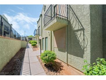 View of building exterior and sidewalk, with balcony above a covered entryway at 7084 Burcot Ave # D27, Las Vegas, NV 89156