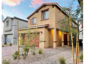 Two-story home featuring a red garage door, complemented by a red front door and a well-maintained landscape at 7892 W Shelbourne Ave, Las Vegas, NV 89113