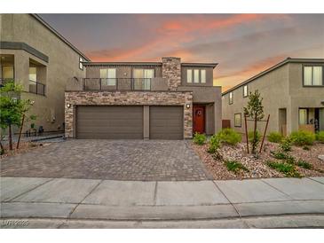 Inviting two-story home featuring a stone facade, three-car garage, balcony and landscaped front yard at 10189 Magnolia Creek St, Las Vegas, NV 89141