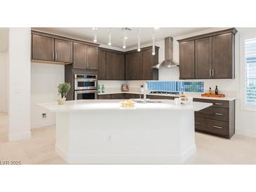 Modern kitchen features dark wood cabinetry, stainless steel appliances, and a large white island with sink at 19 Desert Ivy Ln, Henderson, NV 89011