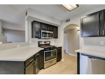 Modern kitchen featuring stainless steel appliances, dark wood cabinets, and light countertops at 698 S Racetrack Rd # 114, Henderson, NV 89015