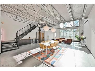 Spacious open-plan living area with soaring ceilings, a modern staircase and a large window view at 5077 Thunder River Cir, Las Vegas, NV 89148