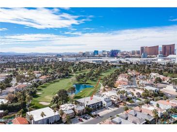 Striking aerial view of home near a golf course, pond and skyline; surrounded by lush landscaping and beautiful blue skies at 915 Vegas Valley Dr # 4, Las Vegas, NV 89109