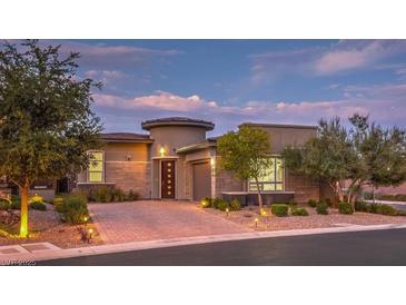 Beautiful home exterior featuring professional landscaping, brick driveway and tasteful outdoor lighting at 9928 Regency Square Ave, Las Vegas, NV 89148