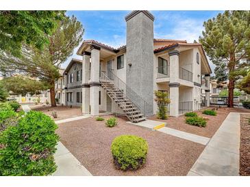 Inviting condo featuring a stucco facade, a decorative chimney, and an external staircase at 1575 W Warm Springs Rd # 413, Henderson, NV 89014