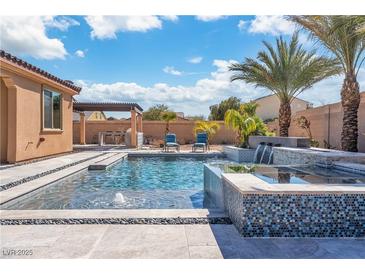 Sparkling pool features tiled spa, waterfall, and a covered outdoor dining area for ultimate relaxation and entertainment at 9091 Becket Ranch Ct, Las Vegas, NV 89113