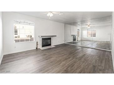 Bright living room features sleek hardwood floors, a modern fireplace and large mirror wall at 5025 Starfinder Ave, Las Vegas, NV 89108