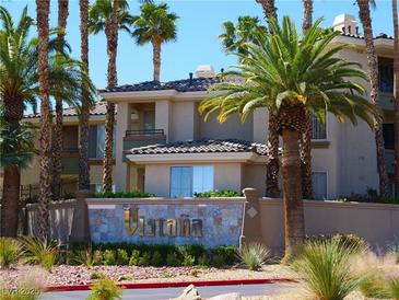 Beautiful multi-story building with lush landscaping, palm trees, and a decorative community sign at 7147 S Durango Dr # 211, Las Vegas, NV 89113